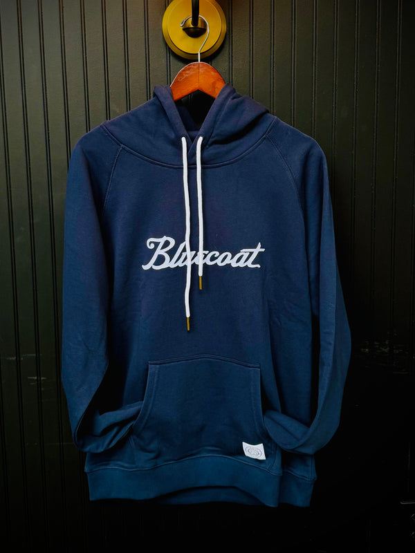 Navy blue hoodie with 'Bluecoat' logo on a wooden hanger against a dark background